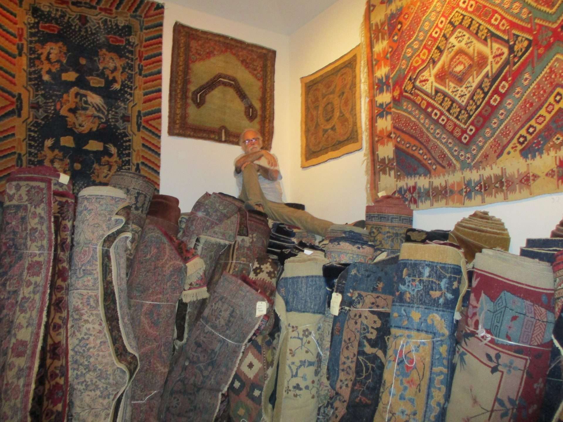 an image of Robert mosby antique rug dealer atop his collection of antique oriental rugs in the Sarasota antique rug gallery